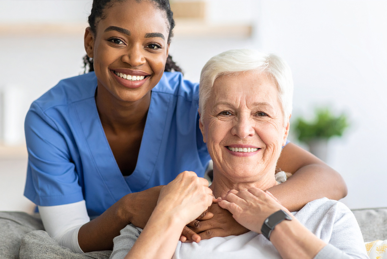 Smiling nurse supports elderly woman with care and compassion.