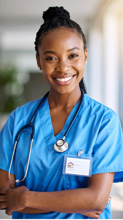 Smiling nurse in blue scrubs with stethoscope and ID badge.