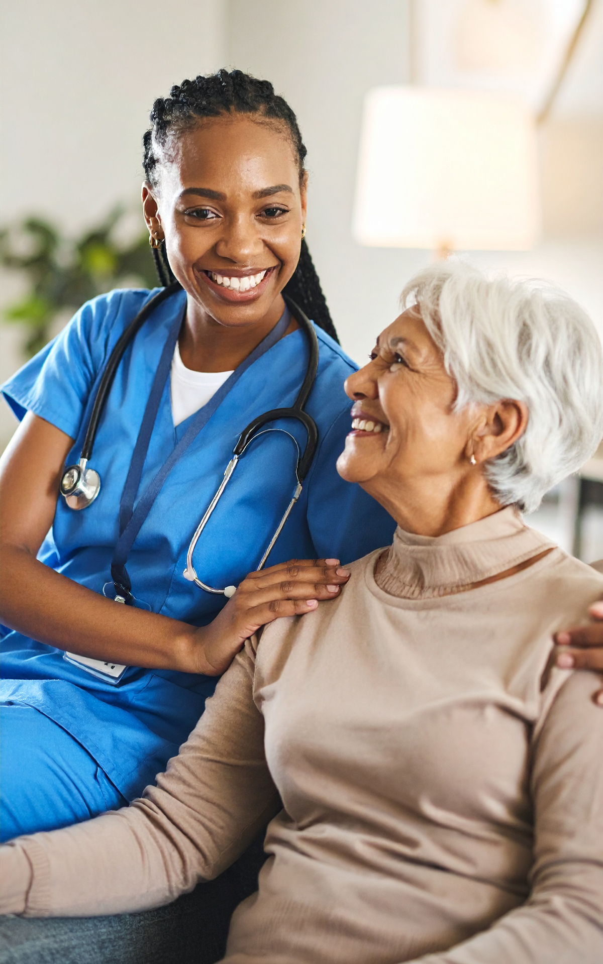 A nurse warmly comforting an elderly woman with a smile.