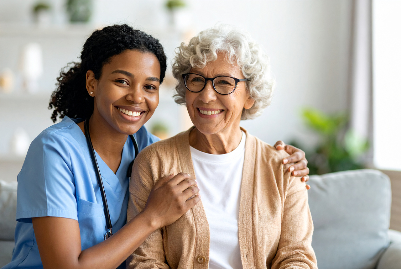 Young caregiver with elderly woman, both smiling warmly.